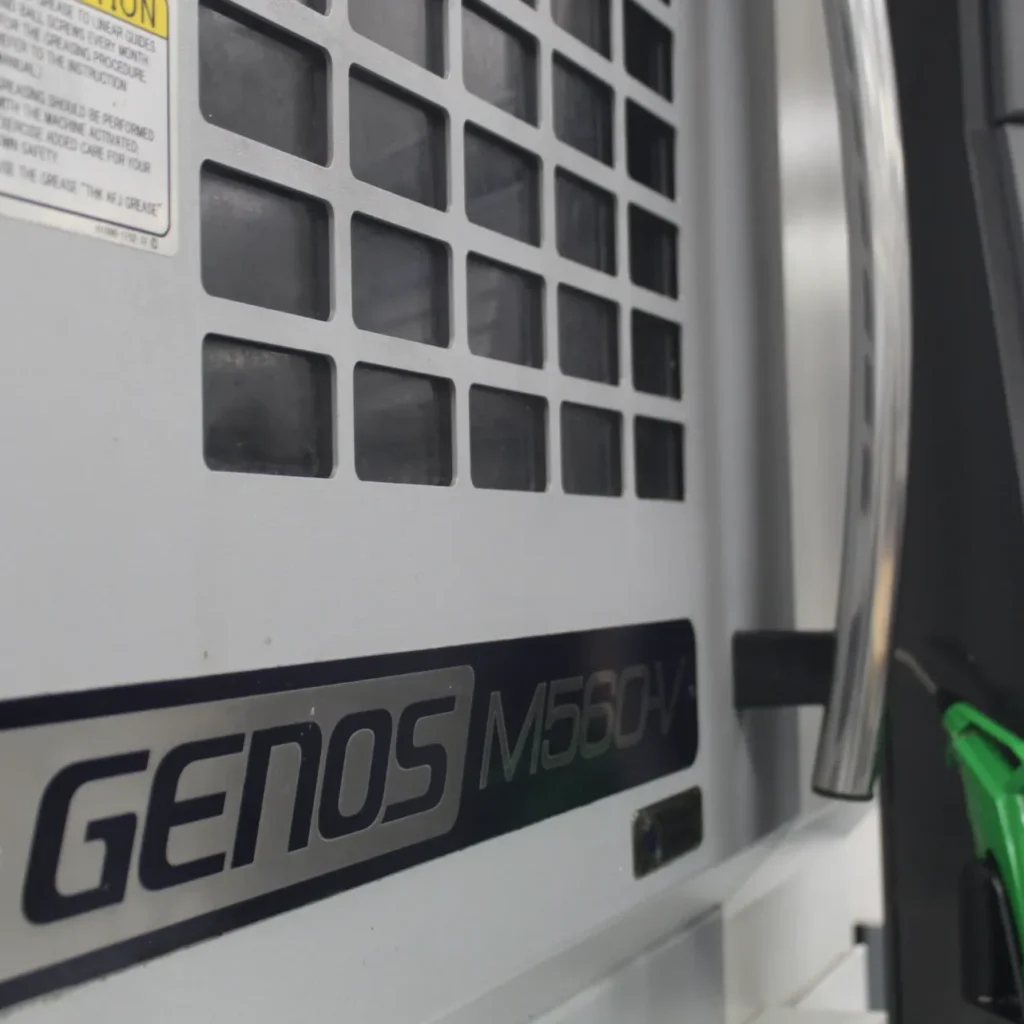 Genos M560V CNC machine control panel in a precision manufacturing facility.